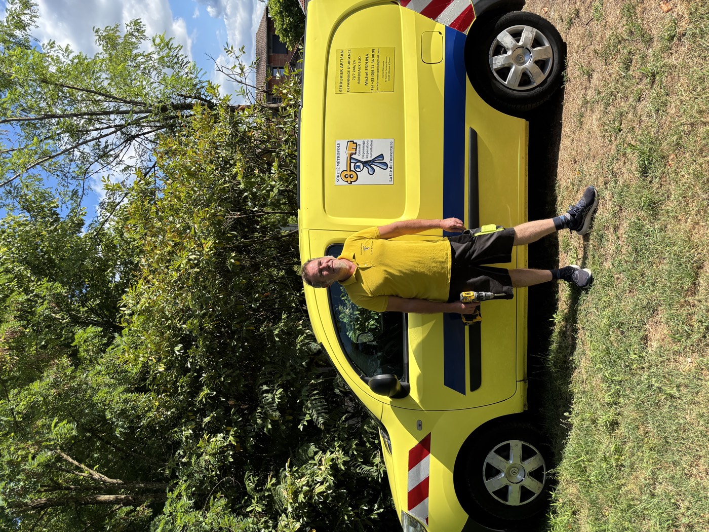 Michel, serrurier artisan, devant son véhicule d'intervention jaune